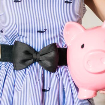 girl holding a piggy bank and wearing dress with bow