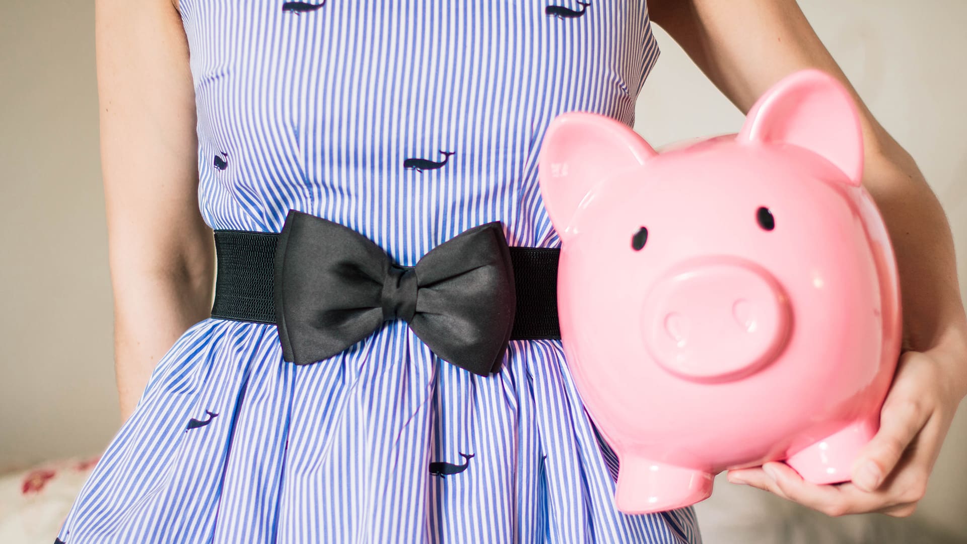 girl holding a piggy bank and wearing dress with bow
