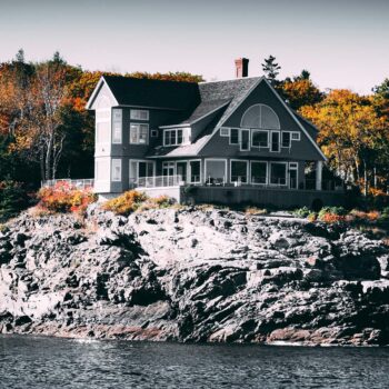 Gray and White House Beside Body of Water on rocks