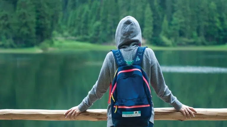 person wearing grey hoodie looking at lake