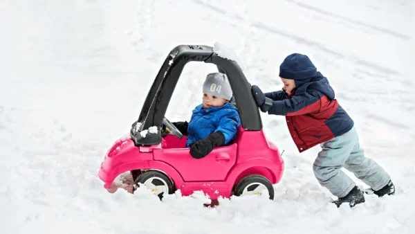 kids playing in toy car in the snow