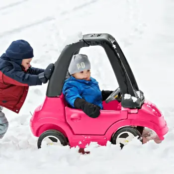 Kids playing in toy car in the snow.
