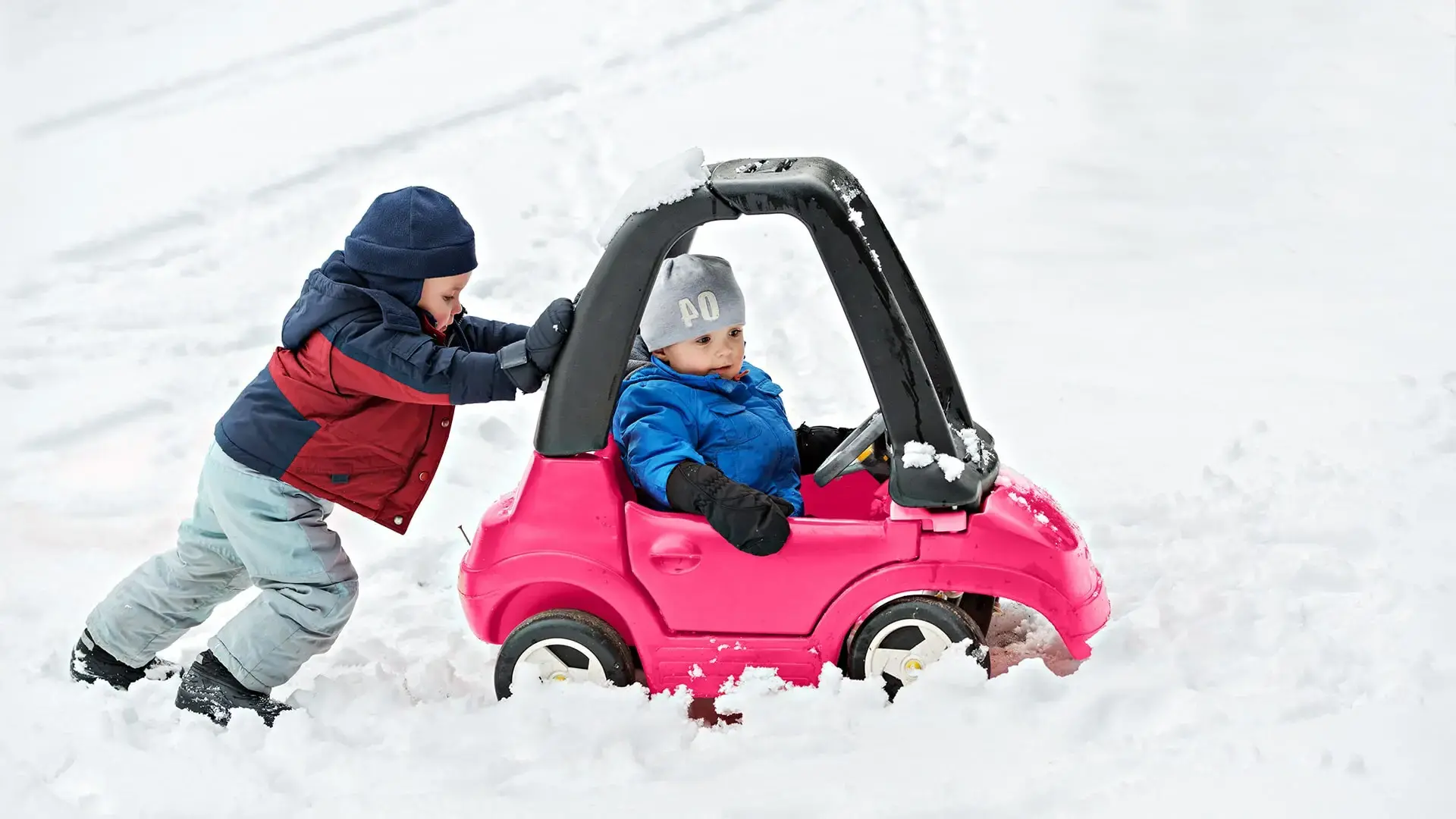 Kids playing in toy car in the snow.