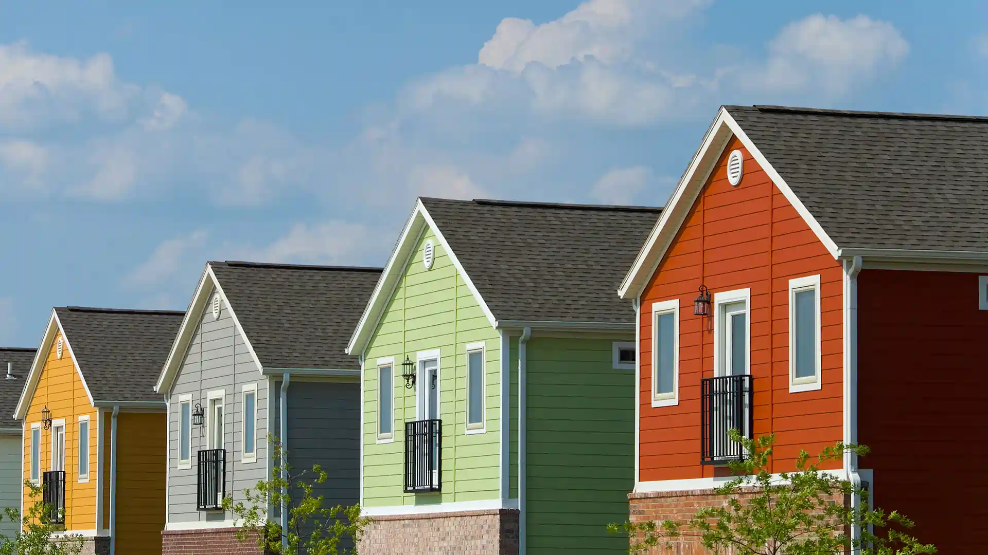 Four colorful houses in a row against a blue sky.