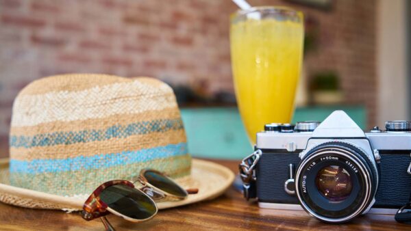 Camera and straw hat sitting on a table on a sunny day