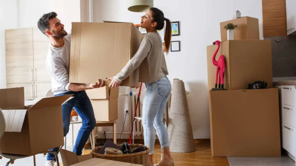 young couple lifting moving boxes in new apartment