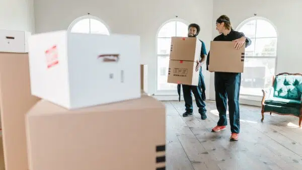 movers carrying boxes in front of stacked boxes