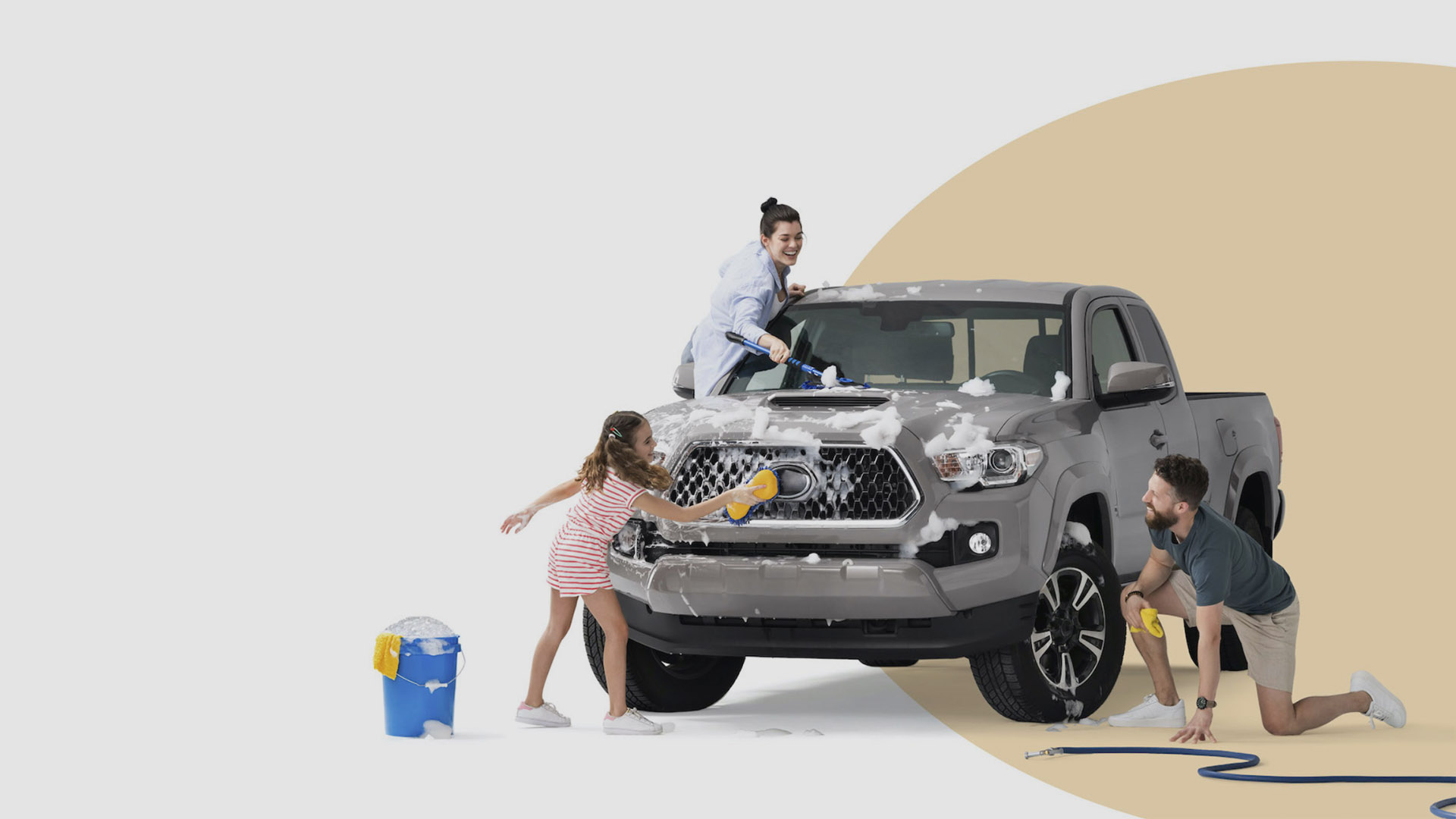 A family having fun while cleaning their truck on a solid white and beige background