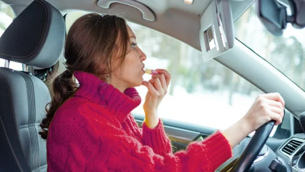female driver applying lip balm behind the wheel