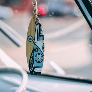 surfboard hanging in rearview mirror of car