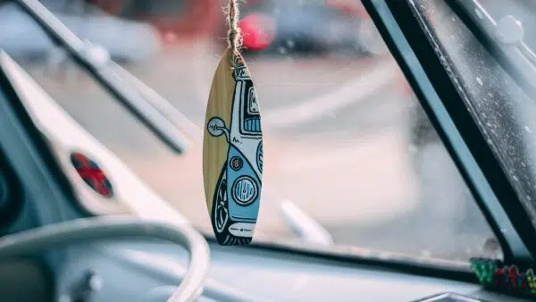 surfboard hanging in rearview mirror of car