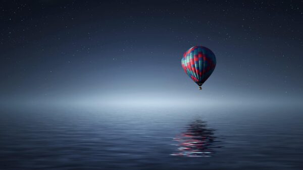 hot air balloon flying over the water