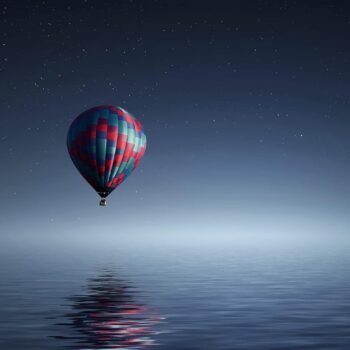 Hot air balloon flying over the water.