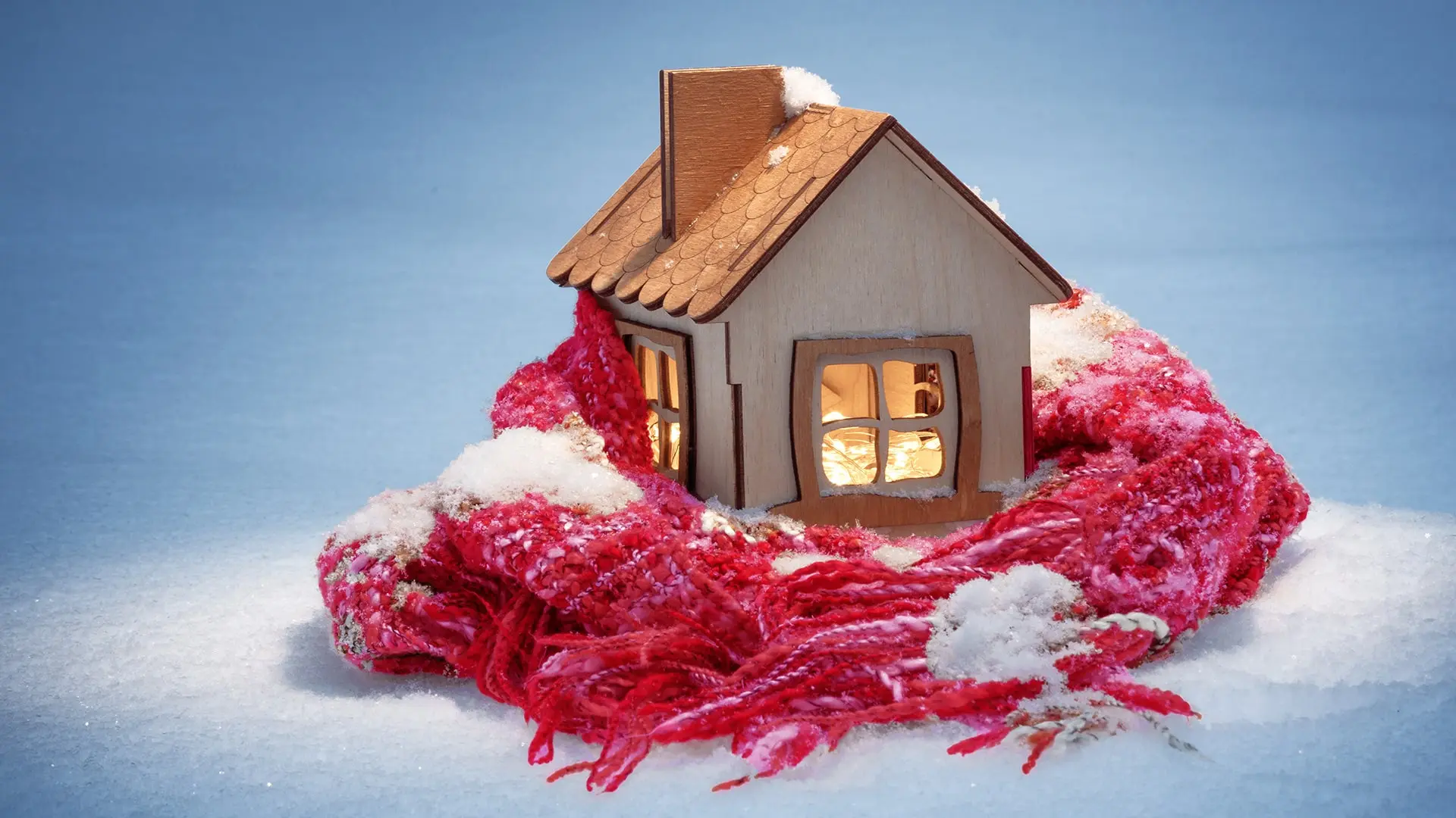 figurine house wrapped in a scarf with snow around it