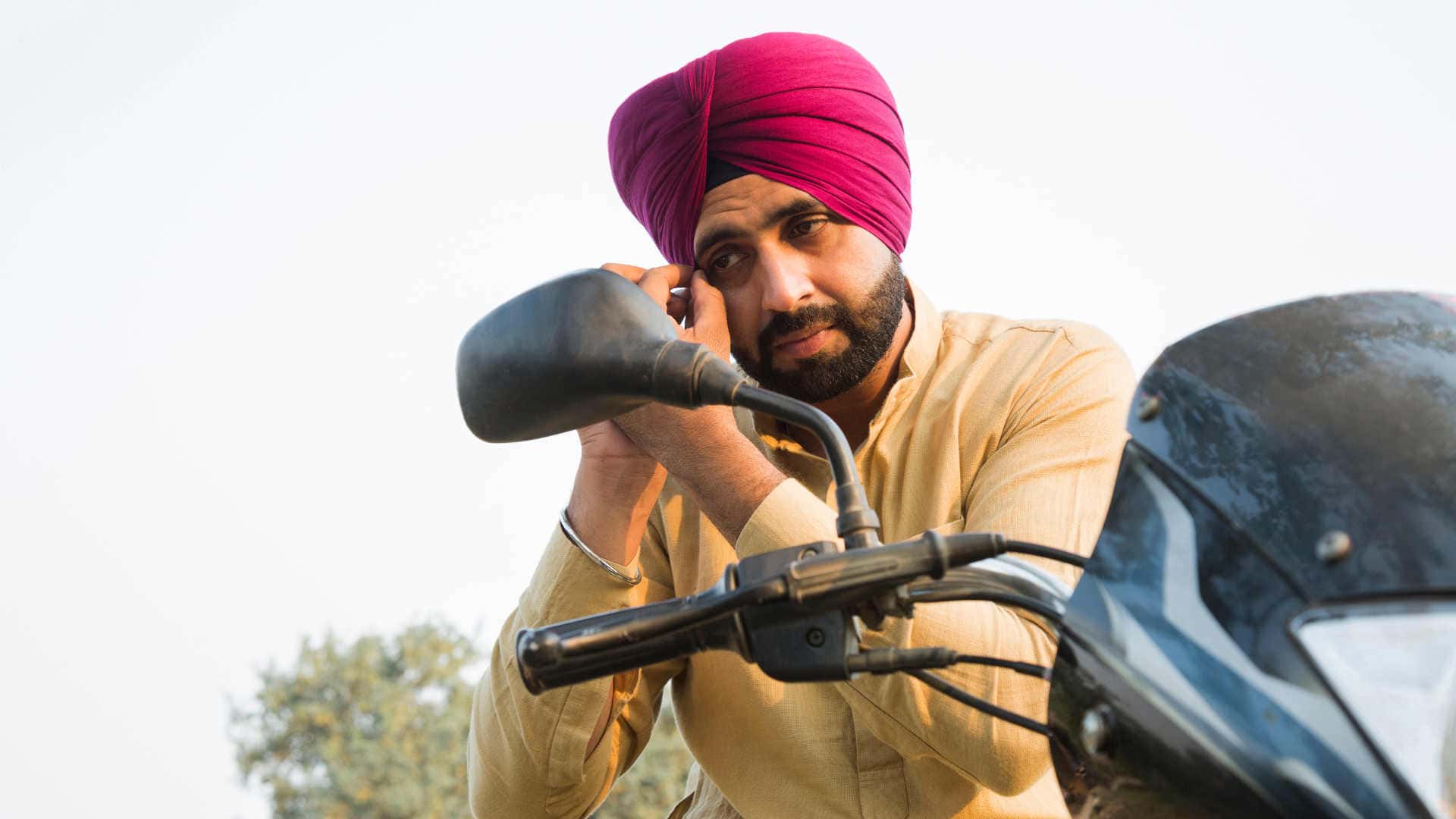 Sikh male on motorcycle wearing turban without a helmet