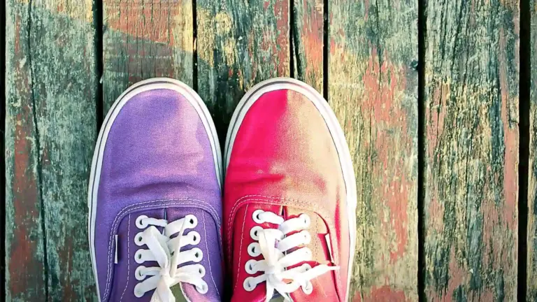 one purple and one pink shoe on a wood plank base