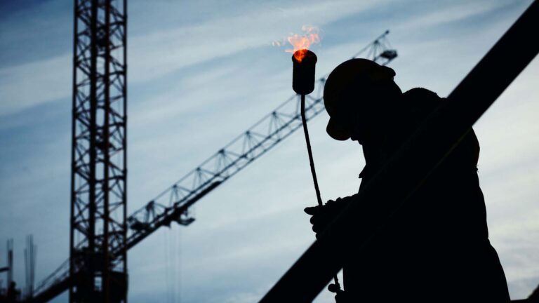 Construction worker on site carrying a blowtorch