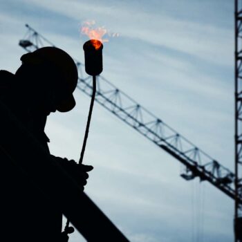 Construction worker on site carrying a blowtorch