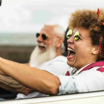 senior couple smiling while driving in a convertible with the top down