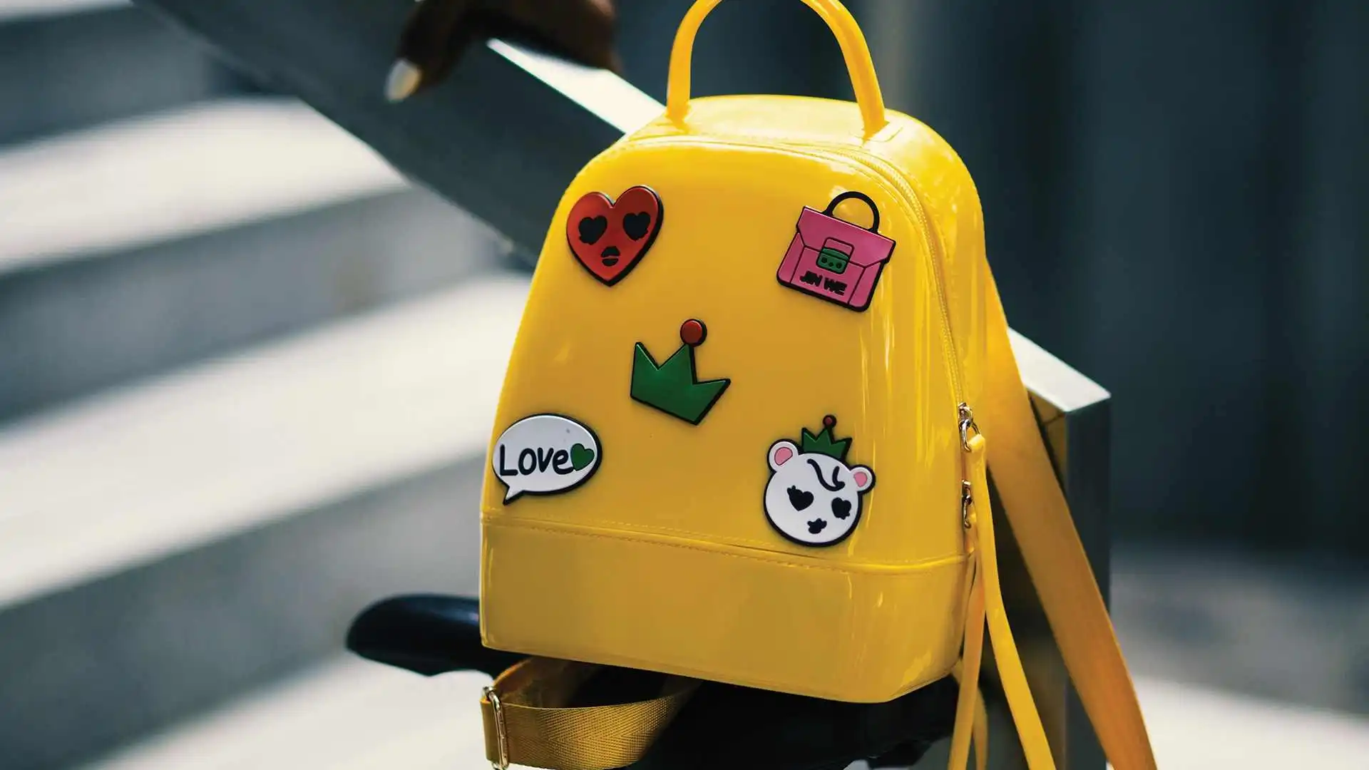 yellow backpack with five stickers on stair rail
