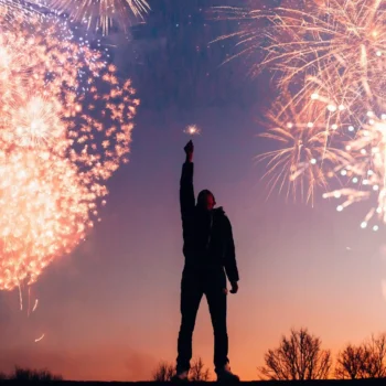 person raising arm with fireworks in the background