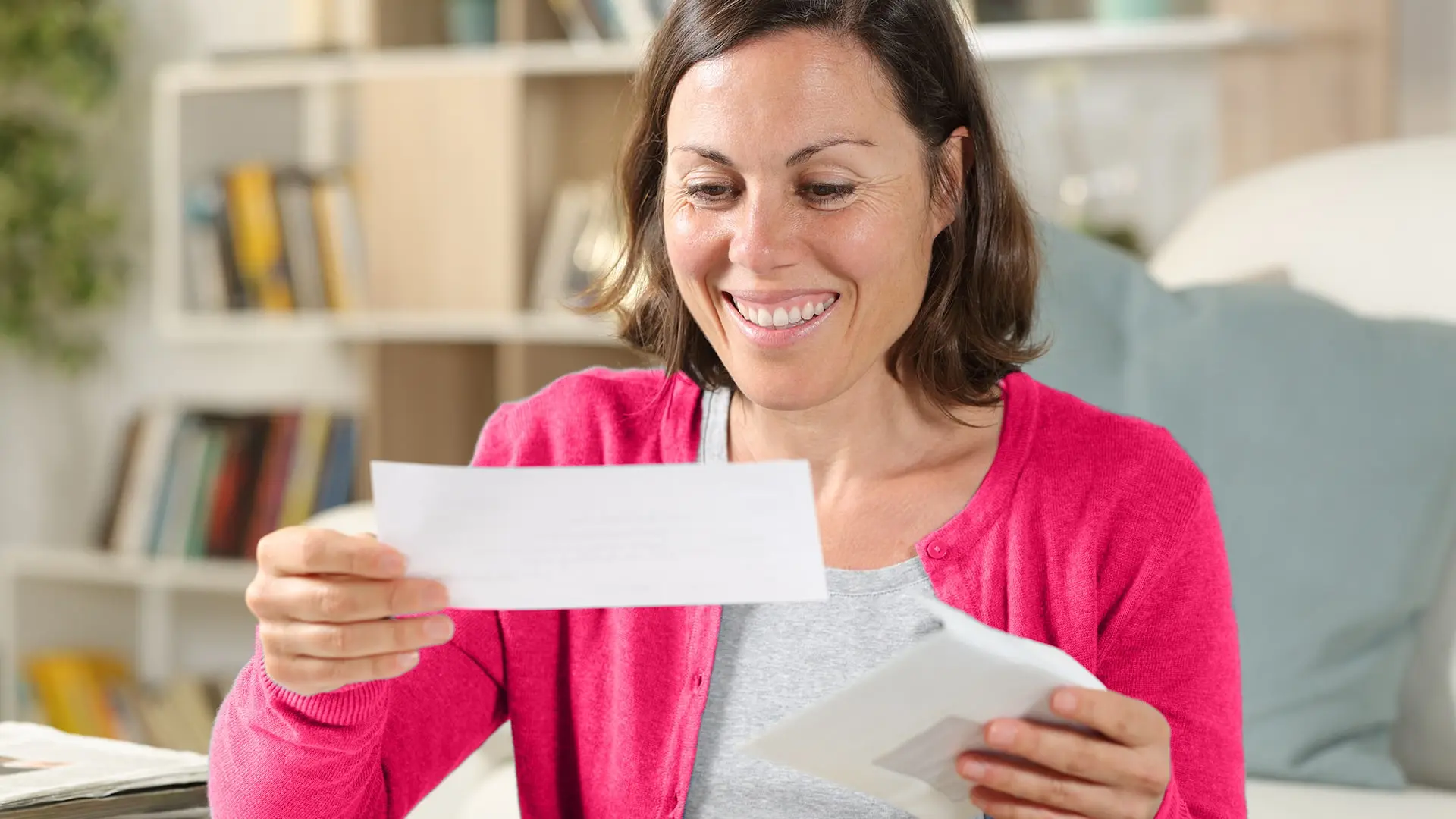 woman smiling while opening envelope with check in it