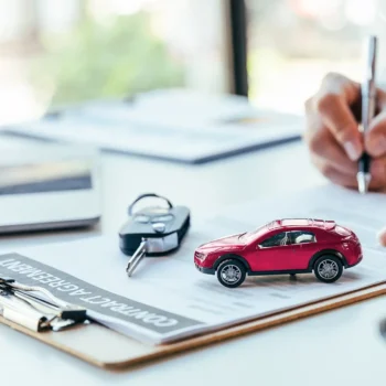 person signing lease contract with car key on paper