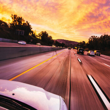 cars ahead on road in sunset