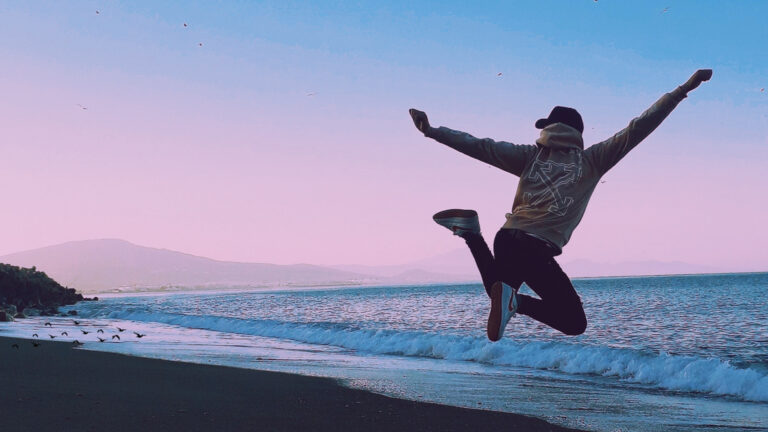 person jumping on a beach in the sunset