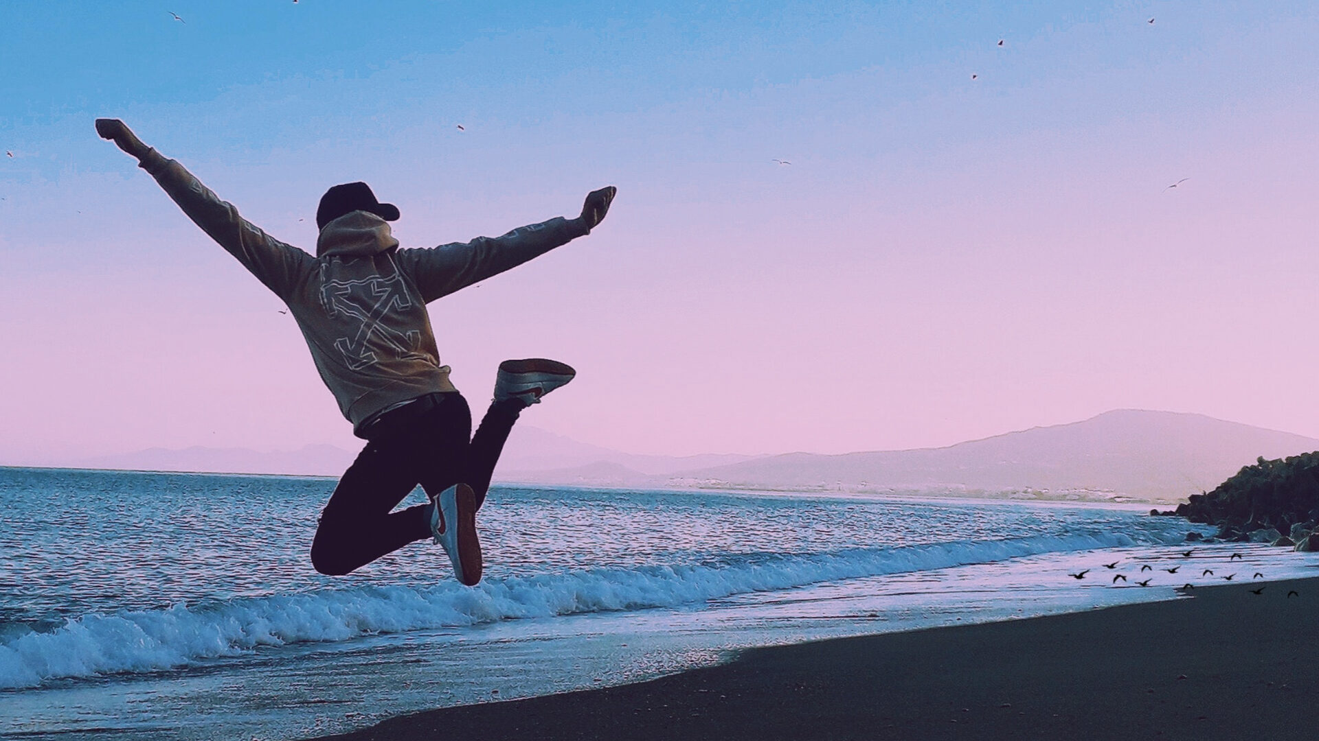 Person jumping on a beach in the sunset.