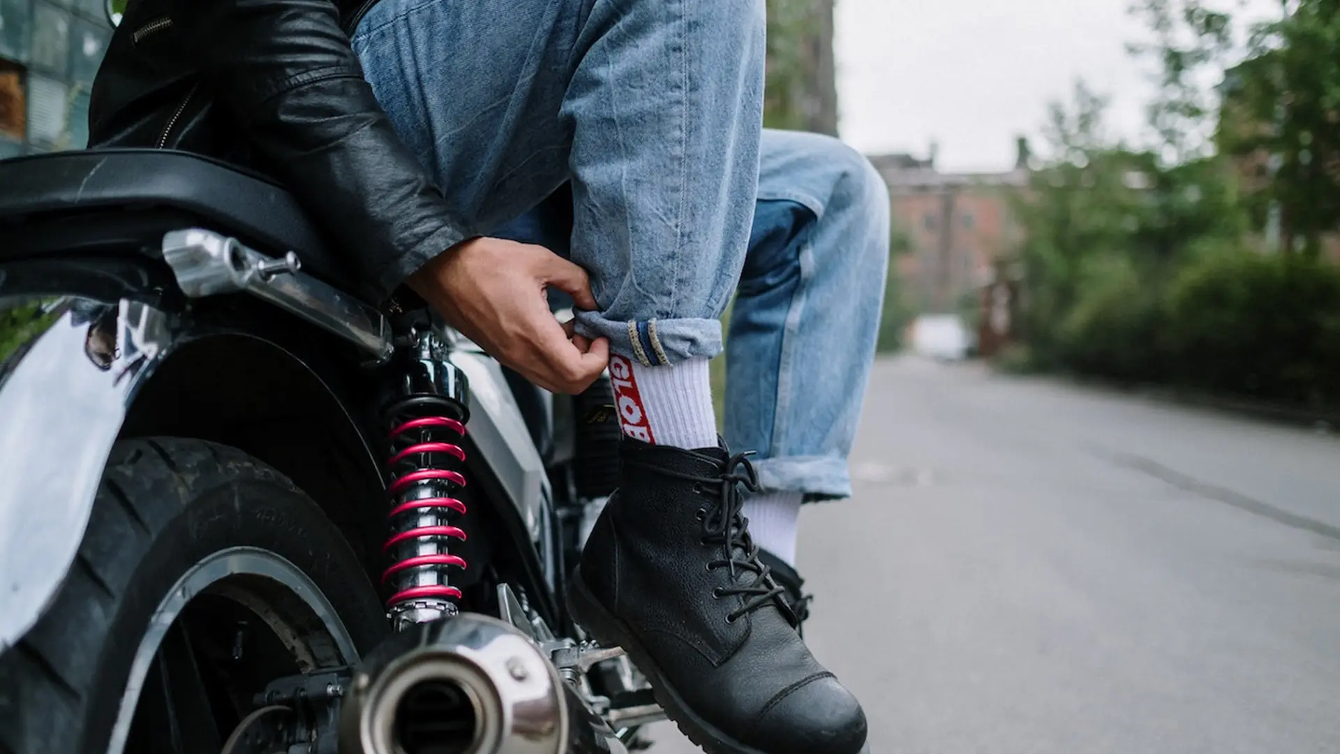 motorcycle rider pulling up socks while sitting on motorcycle parked