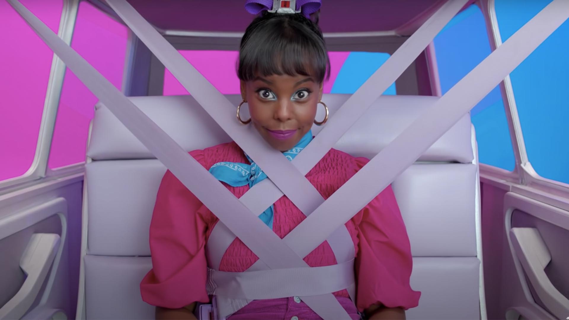 A person comically over-strapped to the seat of a car with a bright pink and blue background