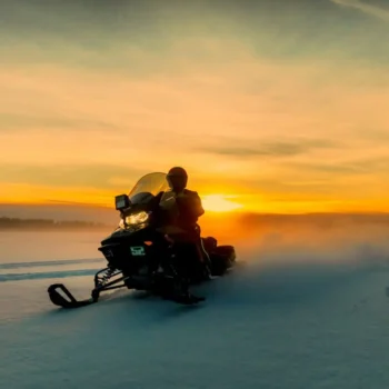 Snowmobile rider driving past a heart in the snow