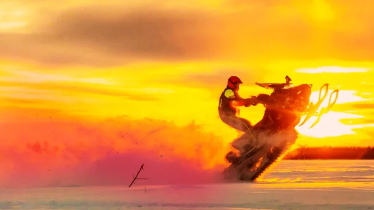 person doing a trick on a snowmobile at sunset