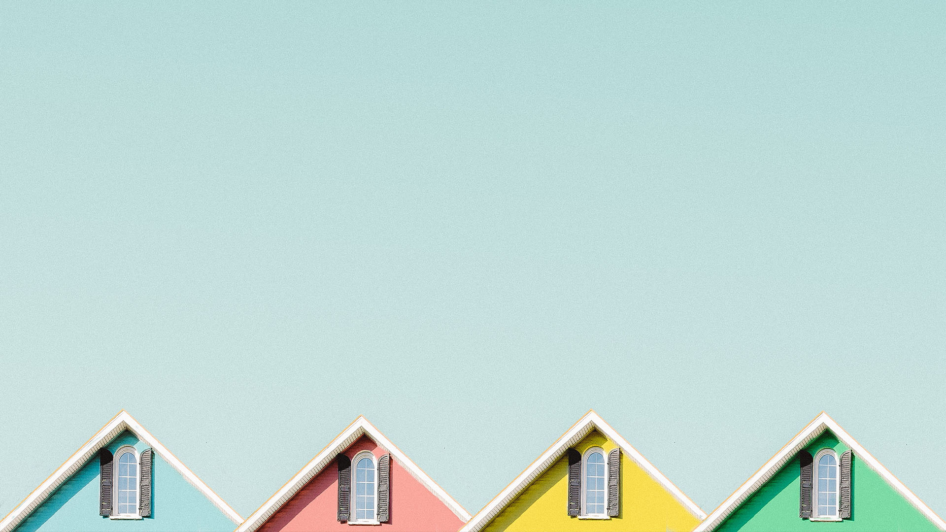 The roofs of four colourful houses in a row on a clear blue day
