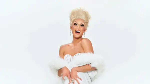 Kyne smiling in a white sequin dress and white boa.