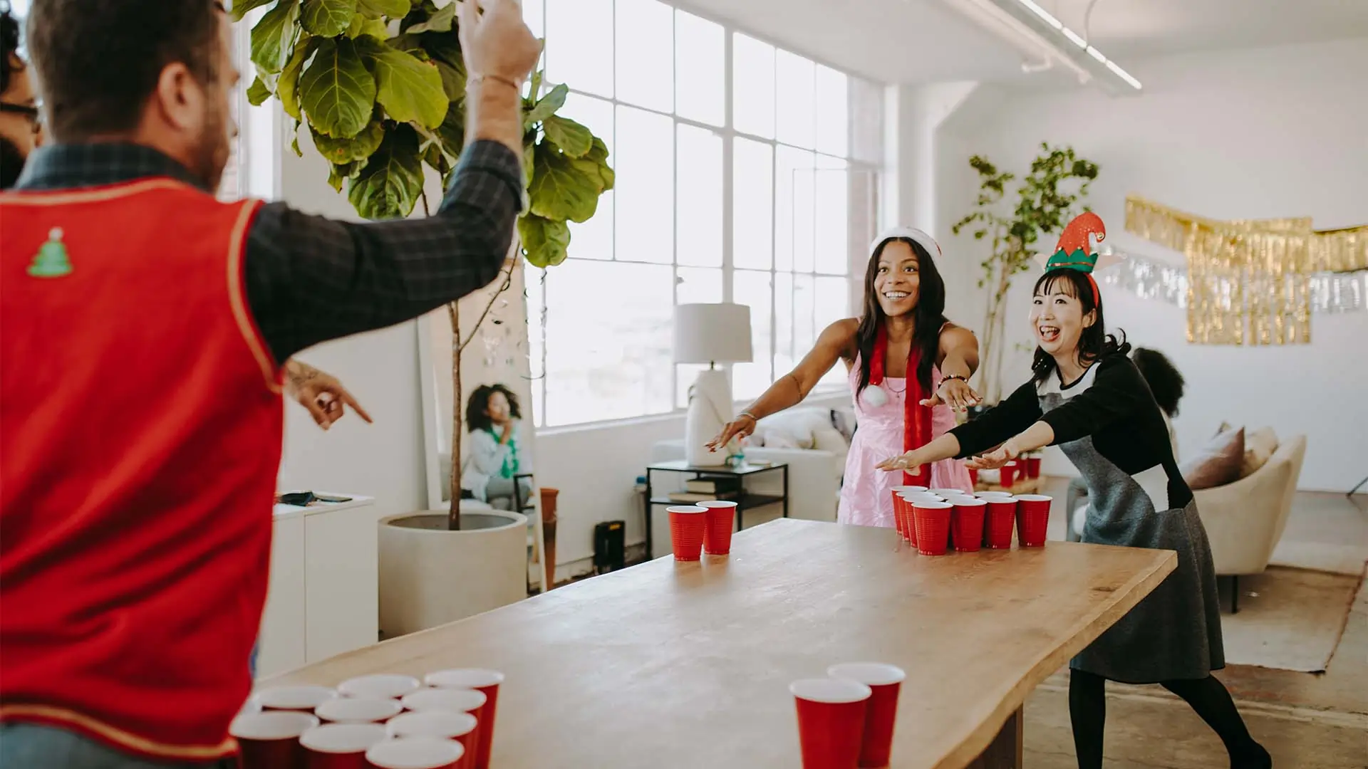 A group of coworkers at a holiday party playing beer pong.