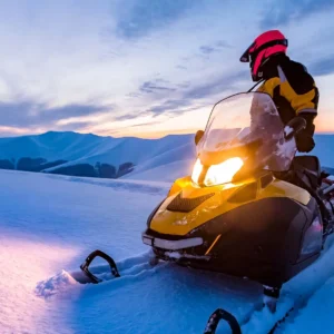 Snowmobile rider looking back at a snowy mountainous landscape.