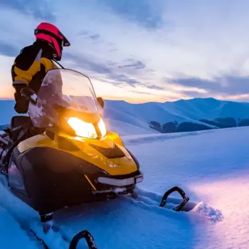 Snowmobile rider looking back at a snowy mountainous landscape.