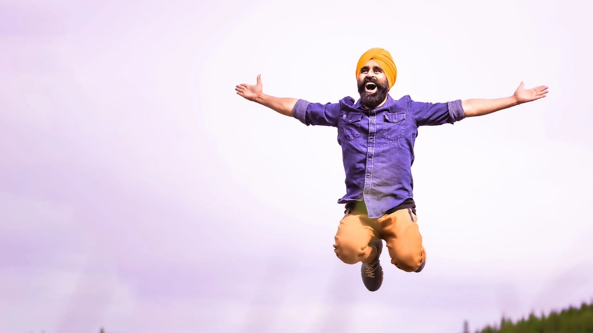 Photo of Gurdeep Pandher jumping in the air with his hands outstretched.