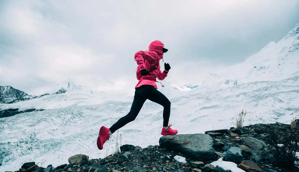 Person running up a mountain in the winter.