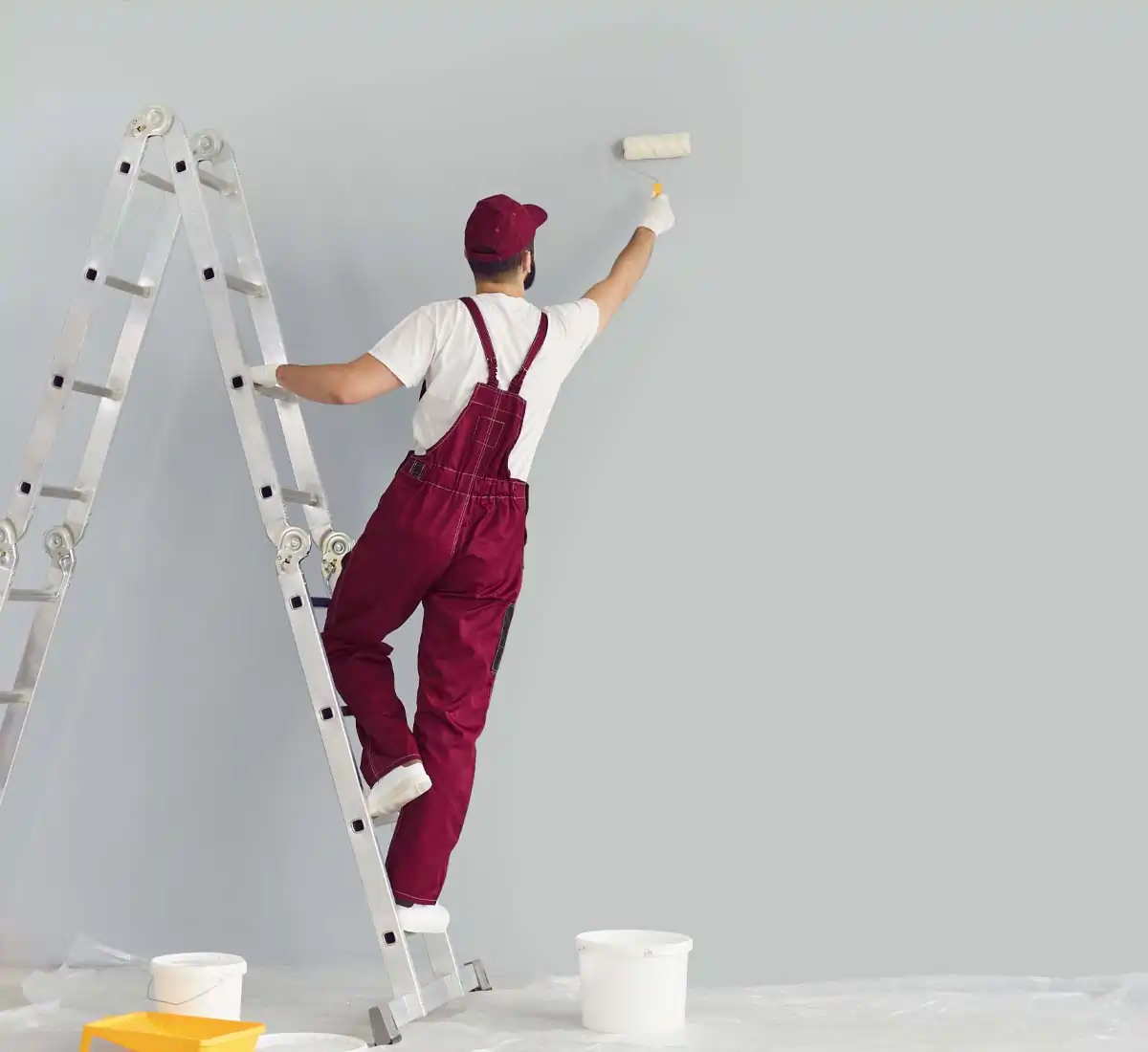 Contractor on a ladder painting wall.