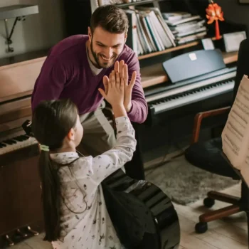 Music teacher high-fiving his young student.