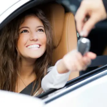 Happy woman getting the keys to her first car.